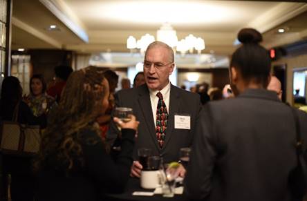 A man and two women chatting and enjoying beverages at a networking event